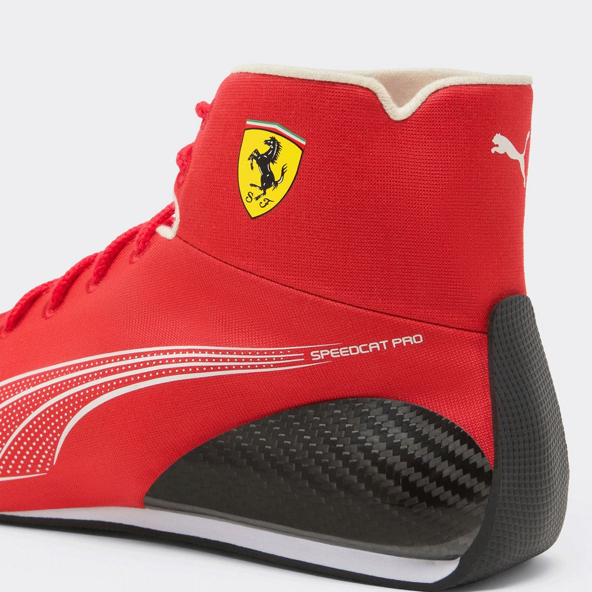 Lewis Hamilton Racing Shoes Replica 2026: a close-up of a red Puma Ferrari Speedcat Pro high-top sneaker, showing the red textile upper, yellow Ferrari shield logo, white Puma cat logo, and a black carbon-fiber-look heel section.