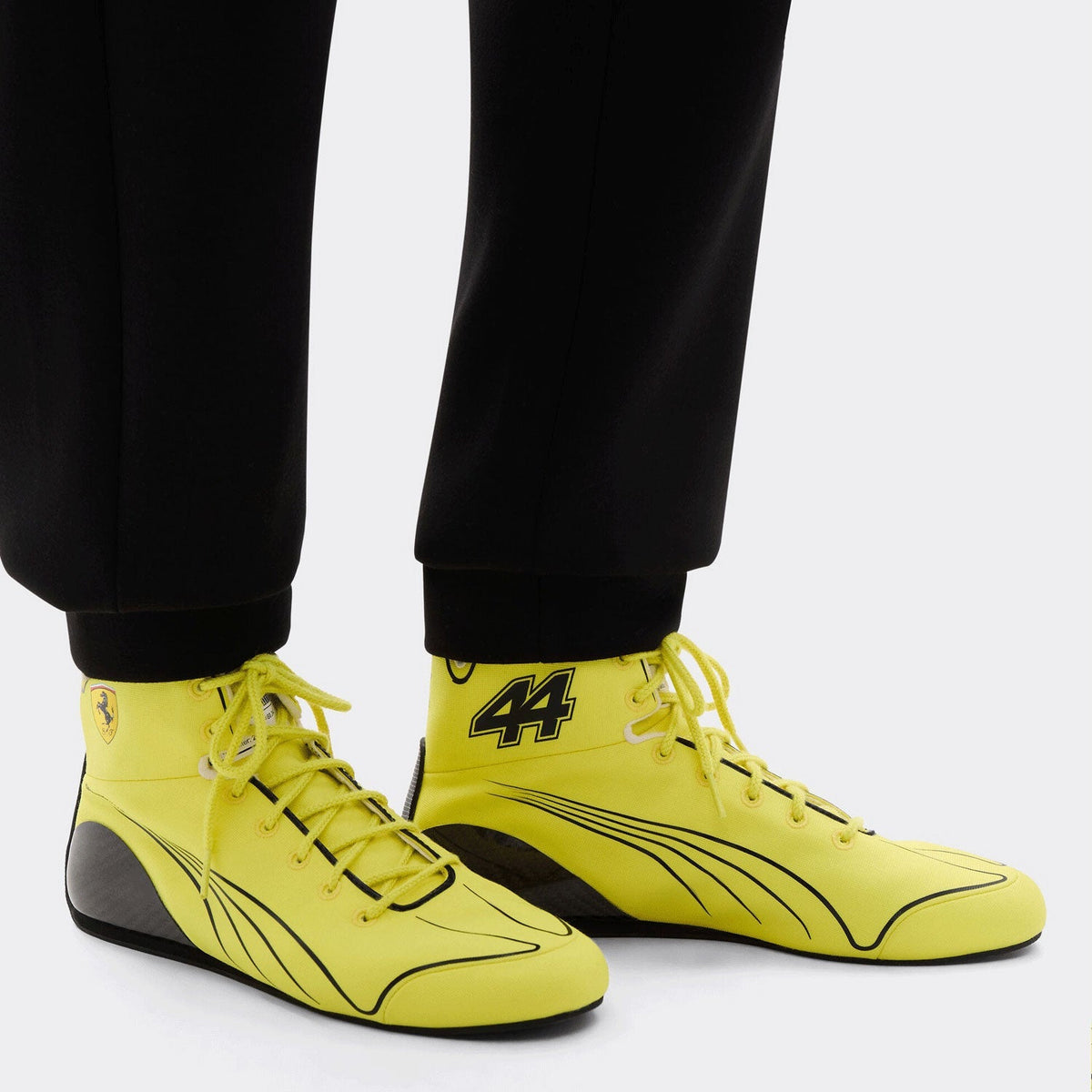 2026 Lewis Hamilton British GP Racing Shoes Replica: a pair of bright yellow high-top racing shoes with black accents and the number 44 on the ankle, worn with black pants.